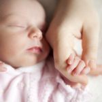 Newborn baby holding mother’s hand