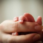 Baby and mother holding hands