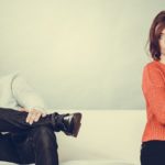 Young couple after quarrel sitting on sofa