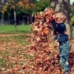 boy-playing-with-fall-leaves-outdoors