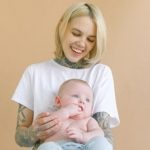 Laughing young mother hugging cute newborn
